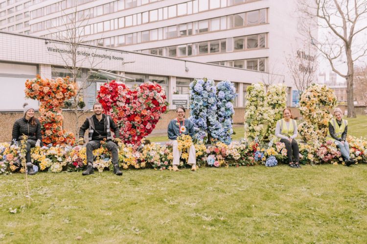 Medical staff sitting outside with flowers spelling I love the NHS