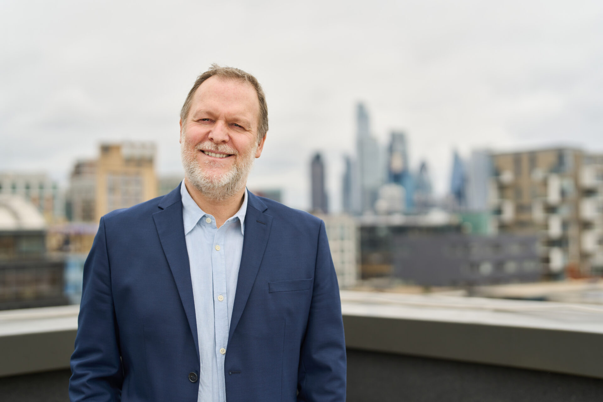 Laurie Lee stands on top of the Guy's & St Thomas' Foundation rooftop, with the City of London skyline in the background